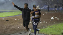 Fußballfans evakuieren ein Mädchen während eines Zusammenstoßes zwischen Fans im Kanjuruhan-Stadion in Malang. Foto: epa/H. Prabowo