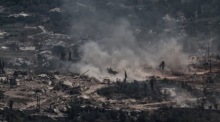 Ein israelischer Panzer manövriert nahe der Grenze zu Libanon, während ein UNIFIL-Konvoi durch das zerstörte Dorf Meiss El Jabal fährt. Foto: EPA/Atef Safadi