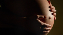 Eine hochschwangere Frau fasst sich mit beiden Händen an ihren Bauch. Foto: Felix Heyder/dpa