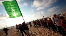 Palästinensische Kinder trainieren neben einer Hamas-Flagge am Strand während eines Sommerlagers der Hamas in Gaza-Stadt. Foto: EPA/Ali Ali