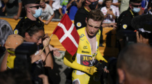 Jonas Vingegaard vom Team Jumbo-Visma aus Dänemark, der das Gelbe Trikot des Gesamtführenden trägt, seine Frau Trine Hansen (l) und ihr Kind Frida reagieren nach der Etappe. Foto: Daniel Cole/Ap/dpa