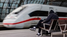 Ein ICE-Zug fährt an einem wartenden Fahrgast im Berliner Hauptbahnhof vorbei. Foto: epa/Clemens Bilan