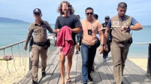 Der des Mordes verdächtigte spanische Koch (2. v. l.) wird von Polizeibeamten eskortiert, als er an einem Hafen ankommt, bevor er zum Gericht auf der Insel Koh Samui gebracht wird. Foto: epa/Somkeat Ruksaman