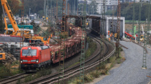 Ein Güterzug passiert eine Baustelle mit einem Schotterbett für neue Gleise. Foto: Oliver Berg/dpa