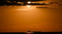 Bei Sonnenuntergang segelt ein Frachtschiff an der Ostseeküste in Rostock-Warnemünde. Foto: epa/Filip Singer