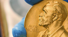 Mitarbeiter der Nationalbibliothek zeigt eine goldene Nobelpreismedaille. Foto: Fernando Vergara/Ap/dpa