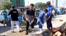 Freiwillige Helfer verteilen Trinkwasser an Menschen am Straßenrand in Karachi. Foto: epa/Rehan Khan