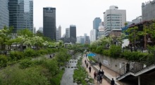Menschen mit Schutzmasken spazieren während der Corona-Pandemie entlang des Cheonggyecheon-Bachs in Seoul. Foto: EPA/Jeon Heon-kyun