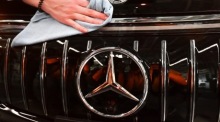 Mercedes Mitarbeiter reinigt das Logo auf einem EQS Auto im Mercedes-Benz Werk Sindelfingen. Foto: epa/Anna Szilagyi