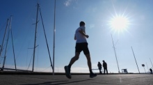 Ein Jogger läuft bei frühlingshaftem Wetter am Sportboothafen an der Kiellinie vorbei. Foto: Marcus Brandt/dpa