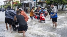 Nach tagelangen Regenfällen stehen Straßen im beliebten Urlaubsort Kuta unter Wasser. Anwohner und Touristen waten durch überflutete Gassen. Foto: epa/Made Nagi