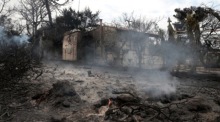Blick auf ein schwelendes Feuer und ein verbranntes Haus (Hintergrund) in Argyra Akti, Mati. Foto: epa/Pantelis Saitas