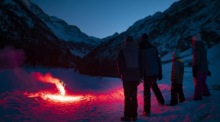 Menschen beobachten ein Feuerwerk im Schnee vor alpinen Bergen während der Silvesterfeierlichkeiten im Alpenort Zinal. Foto: EPA-EFE/Laurent Gillieron