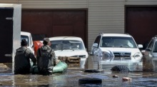 Anwohner inspizieren ihr Auto in einem überfluteten Wohngebiet in Orenburg. Foto: EPA-EFE/Stringer