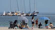 Menschen genießen das Sommerwetter am Ostseestrand. Foto: Markus Scholz/dpa