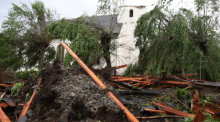 Trümmer liegt vor der katholischen Kirche St. Clemens in Hellinghausen bei Lippstadt, deren Spitze zerstört wurde. Ein mutmaßlicher Tornado hat in Lippstadt am Freitagnachmittag massive Schäden verursacht. Foto: Friso Gentsch/dpa