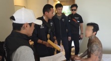 Ermittler der Einwanderungsbehörde eröffnen dem südkoreanischen Verdächtigen den Durchsuchungsbeschluss in seiner Wohnung in Pattaya. Bild: TMN.TV