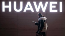In Shanghai geht eine Frau an einem Huawei-Logo vorbei. Foto: epa/Alex Plavevski