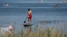 Ein Mann fährt bei großer Hitze mit einem Paddleboard über den Piaseczno-See in Ostpolen. Foto: EPA/Wojtek Jargilo