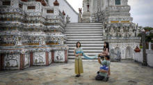 Touristen posieren – gekleidet in traditionellen Kostümen – für ein Foto im Wat Arun am Ufer des Chao-Phraya-Flusses in Bangkok. Foto: epa/Diego Azubel