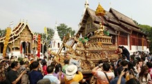 Besucher verfolgen in Chiang Mai eine traditionelle Songkran-Prozession mit geschmückter Buddha-Figur vor Tempelkulisse. Foto: epa/Pongmanat Tasiri