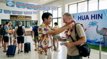 Ein Reisender wird am Flughafen Hua Hin mit einer traditionellen Girlande und einer Wasserpistole freudig zum Songkran-Fest 2026 begrüßt. Foto: Der Farang (ai)
