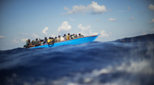Migranten sitzen in einem Holzboot südlich der italienischen Insel Lampedusa auf dem Mittelmeer. Foto: Francisco Seco/Ap/dpa
