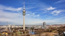 Olympiapark München mit seinem ikonischen Olympiaturm und dem Zeltdach des Stadions, errichtet für die Olympiade 1972, vor der Münchner Stadtsilhouette. Foto: Pixabay/Jürgen