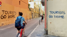 Ein an eine Wand im Künstlerviertel Vila de Gràcia gesprühter Schriftzug «Tourists Go Home». Foto: Emilio Rappold/dpa