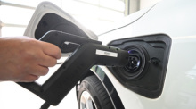 Ein Mitarbeiter lädt in einer Prüfhalle von Dekra in Stuttgart ein Elektroauto während einer technischen Untersuchung auf. Foto: Bernd Weißbrod/dpa