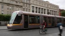 Eine Radfahrerin überholt eine Dubliner Luas Tram in Dublin. Foto: epa/Adam Vaughan