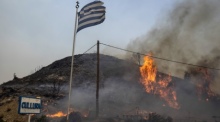 Flammen lodern auf einen Hügel. Die Bilder der Brände auf Rhodos gingen um die Welt. Doch die Urlauber bleiben der «Sonneninsel» treu. Foto: Petros Giannakouris/Ap/dpa