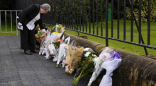 Eine Frau betrachtet Blumen die vor dem Gouvernement House nach dem Tod von Königin Elizabeth II. niedergelegt wurden. Die britische Königin Elizabeth II. ist tot. Foto: Mark Baker