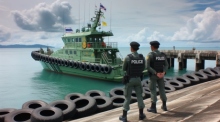 Die thailändische Polizei wartet am Pier in Sattahip, Chon Buri, auf die Inspektion eines der fünf beschlagnahmten Schiffe mit unversteuertem Öl. Foto generiert von OpenAI's DALL·E