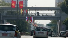 Fahrzeuge passieren eine Straße in Yangon, während Menschen am fünften Jahrestag des Militärputsches auf einer Fußgängerbrücke stehen. Foto: epa/Nyein Chan Naing