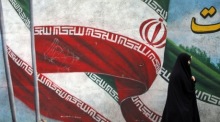 Eine Frau geht an einem Bild der iranischen Nationalflagge in Teheran vorbei. Foto: epa/Abedin Taherkenareh