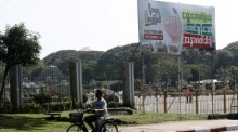 Ein Mann fährt in Yangon an einem Wahlplakat vorbei. Aktivisten rufen zu einem landesweiten «stillen Streik» gegen die Wahlpläne der Militärjunta auf. Foto: epa/Nyein Chan Naing