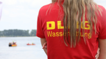 Ein Mitglied der Deutschen-Lebens-Rettungs-Gesellschaft (DLRG) beobachtet eine Rettungsübung auf dem Rhein. Foto: Sascha Thelen/dpa