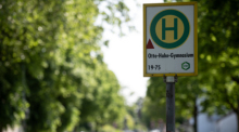 Auf dem Haltestellenschild nahe der Unfallstelle steht "Otto-Hahn-Gymnasium". In der Nähe einer Dinslakener Schule sind nach einem schweren Unfall zwei Kinder gestorben. Foto: Fabian Strauch/dpa