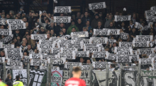 Fans von Wolfsburg protestieren mit Plakaten gegen die Zerstückelung der Spieltage. Foto: Patrick Seeger/dpa