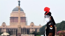 Ein Polizist der Militärpolizei mit Gesichtsschutz steht vor dem indischen Präsidentenhaus in Neu-Delhi Wache. Foto: epa/Str