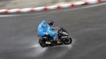 Motorradfahrer kämpfen sich während eines heftigen Regenschauers durch eine überflutete Straße. Die Behörden warnen vielerorts vor Starkregen und Sturzfluten. Foto: epa/Rungroj Yongrit