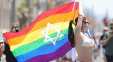 Ein Teilnehmer trägt bei der Pride-Parade in Tel Aviv eine Regenbogenflagge mit Davidstern. Die Veranstaltung kehrte nach zweijähriger Pause an die Strandpromenade zurück. Foto: Abir Sultan/epa/dpa