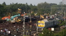Menschen beobachten die Stelle, an der die Züge im Bezirk Balasore im ostindischen Bundesstaat Orissa entgleist sind. Foto: Rafiq Maqbool/Ap