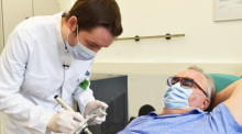 Nuklearmediziner Martin Heuschkel trägt radioaktive Paste beim Patienten Rainer Schnabel auf, die einen Hautkrebs-Tumor abtöten soll. Foto: Unimedizin Rostock/dpa