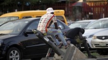 Ein Mann sitzt auf einem kaputten Mast einer Straßenlaterne im Stadtteil Oshodi in Lagos. Foto: epa/Akintunde Akinleye