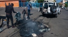 Angestellte der Stadtverwaltung sammeln die Überreste einer verbrannten Leiche ein, die auf einer Straße in Port-au-Prince gefunden wurde. Foto: epa/Johnson Sabin