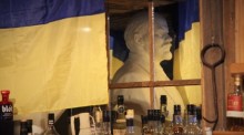 Eine Ukraine-Flagge hängt im Restaurant Kroa in Longyearbyen vor einer Büste des russischen Revolutionsführers Wladimir Iljitsch Lenin, die in einem Spiegel zu sehen ist. Foto: Steffen Trumpf/dpa