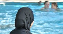 Eine muslimische Schülerin sitzt in einem Ganzkörperbadeanzug (Burkini) am Rande eines Schwimmbeckens. In Frankreich ist erneut ein Streit um Burkinis ausgebrochen. Foto: Rolf Haid/dpa