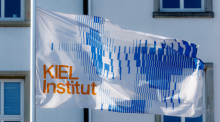 Eine Fahne mit der Aufschrift «KIEL Institut» weht vor dem Gebäude des Kiel Instituts für Wirtschaft. Foto: Markus Scholz/dpa